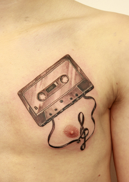 Black And Grey Cassette Tattoo On Man Chest By Heinz Graynd