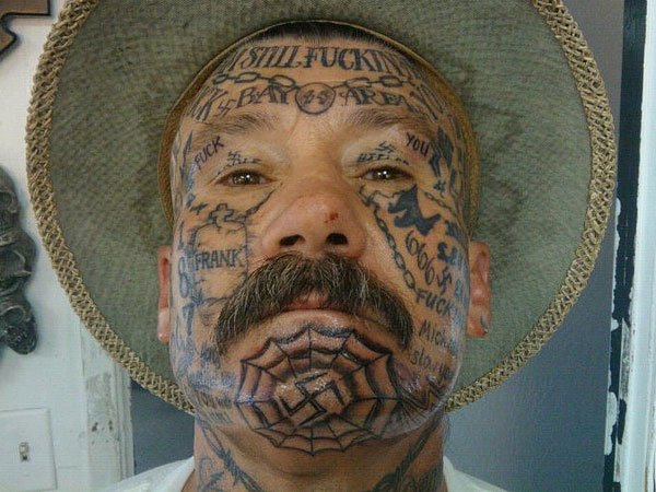 Black Swastika In Web Tattoo On Man Chin
