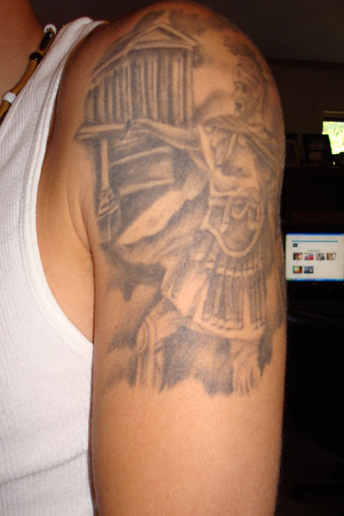 Grey Ink Greek Warrior Tattoo On Man Left Shoulder