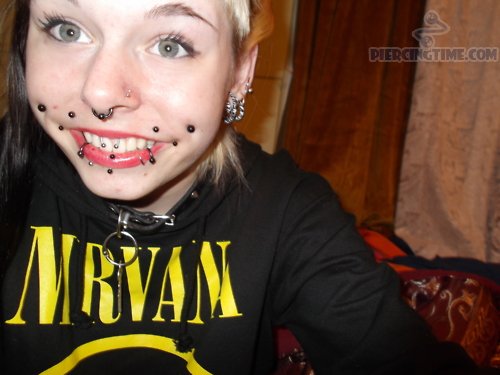Smiling Girl With Multiple Face Piercings And Canine Bites Piercing