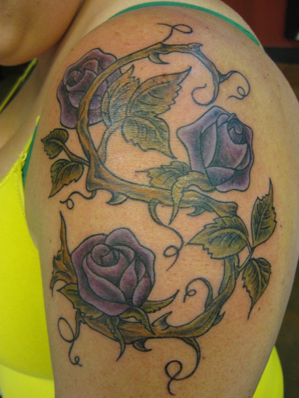 Three Purple Rose With Vine Tattoo On Girl Left Shoulder