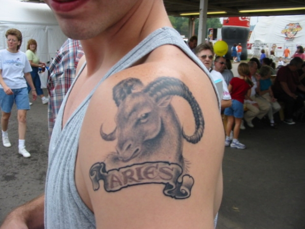 Black And Grey Aries Head With Banner Tattoo On Man Left Shoulder