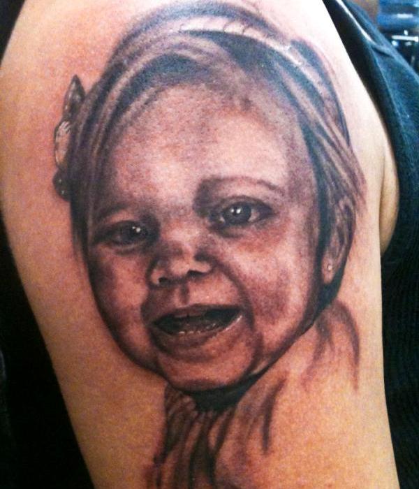 Black And Grey Smiling Baby Portrait Tattoo On Shoulder