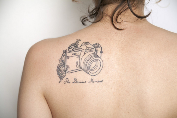 Black Camera Tattoo On Girl Left Back Shoulder