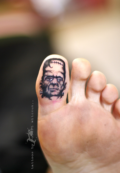 Black Ink Portrait Tattoo On Under Toe By Robert Witczuk
