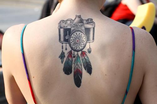 Camera With Three Feather Tattoo On Girl Upper Back