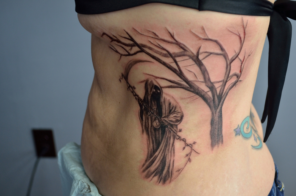 Grim Reaper And Tree Without Leaves Tattoo On Girl Side Rib