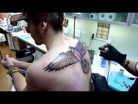 Black Ink Flying Falcon Tattoo On Man Upper Back