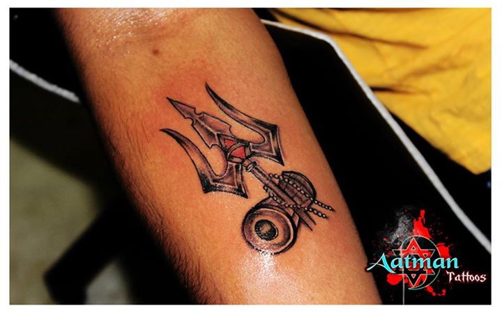 Black Ink Trishul With Pellet Drum Tattoo On Forearm