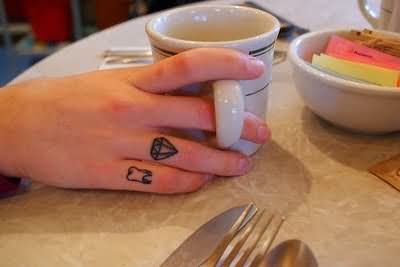 Black Outline Diamond And Teeth Tattoo On Finger