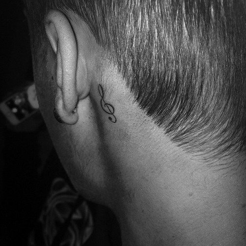 Black Treble Clef Tattoo On Man Behind The Ear