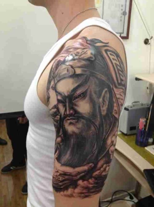 Black Ink Asian Warrior Head Tattoo On Man Left Half Sleeve