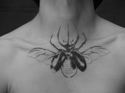 Black Ink Beetle Tattoo On Collarbone