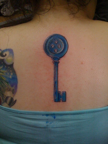 Blue Ink Button Key Tattoo On Girl Upper Back