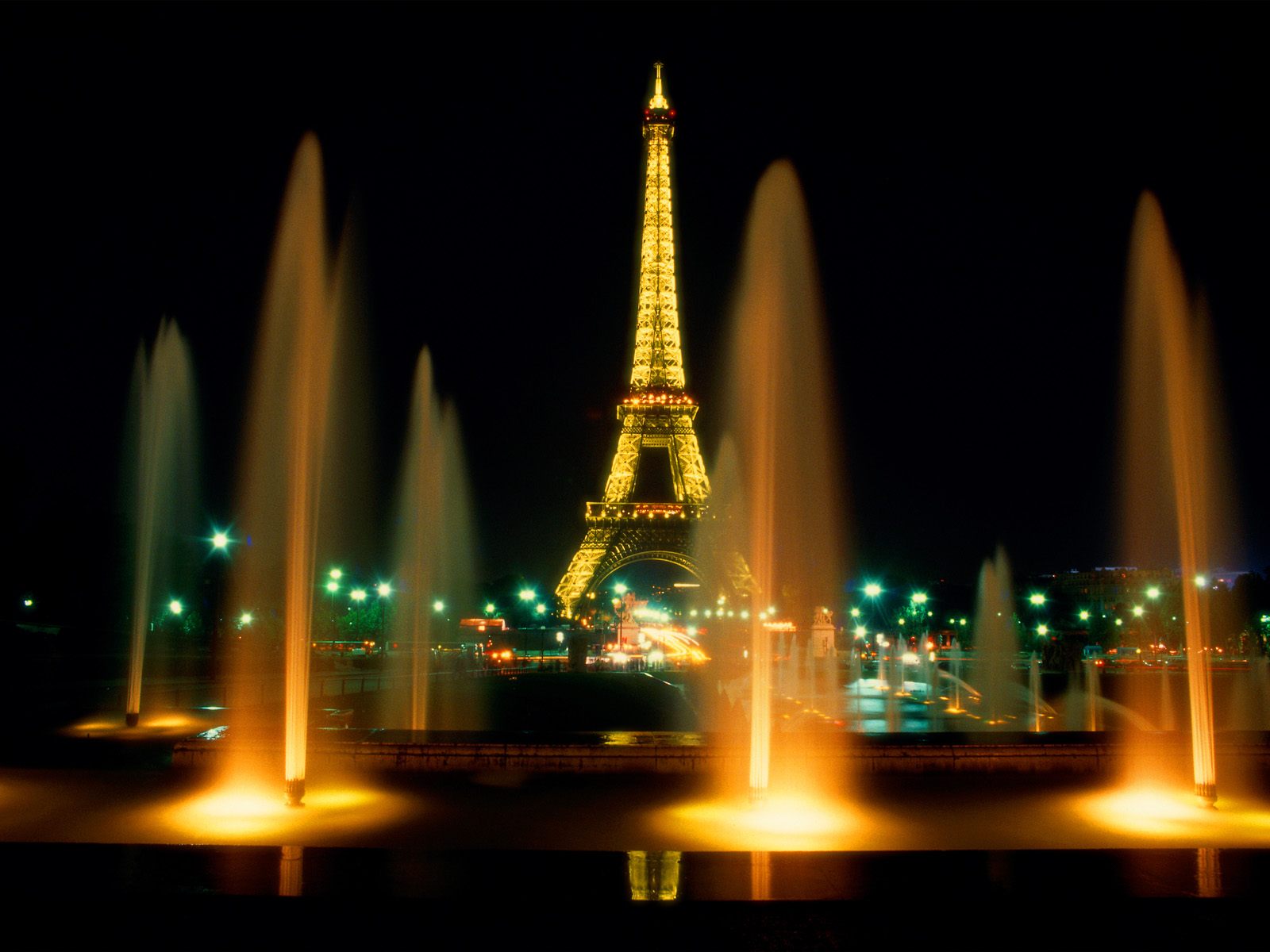 Glowing Eiffel tower and fountains at night