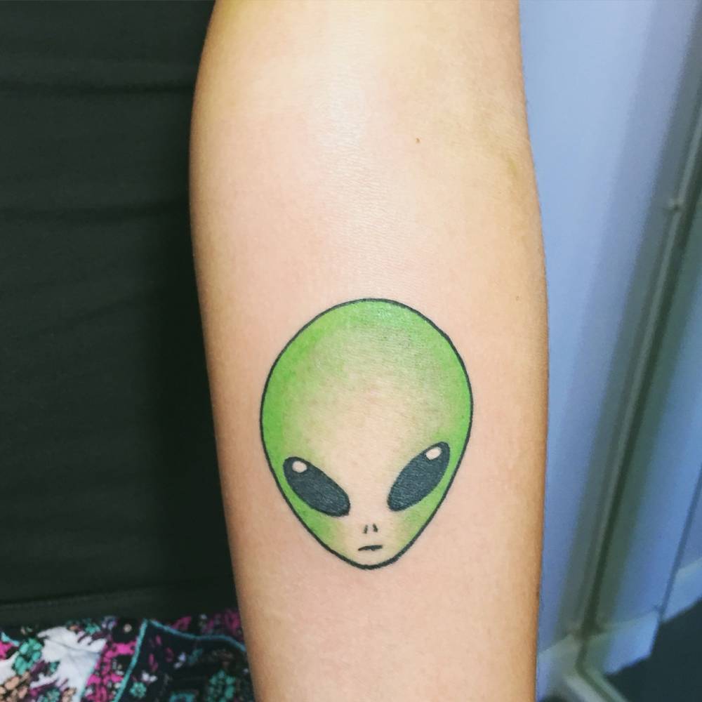 Green Alien Head Tattoo On Left Forearm