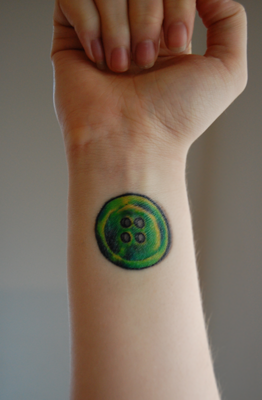 Green Ink Button Tattoo On Wrist By Decay