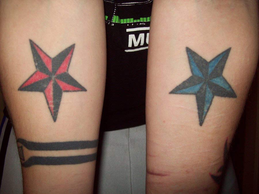 Red Nautical Star And Blue Nautical Star Tattoos On Forearm