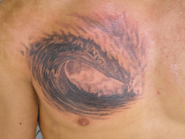 Black And Grey Wave Tattoo On Man Chest