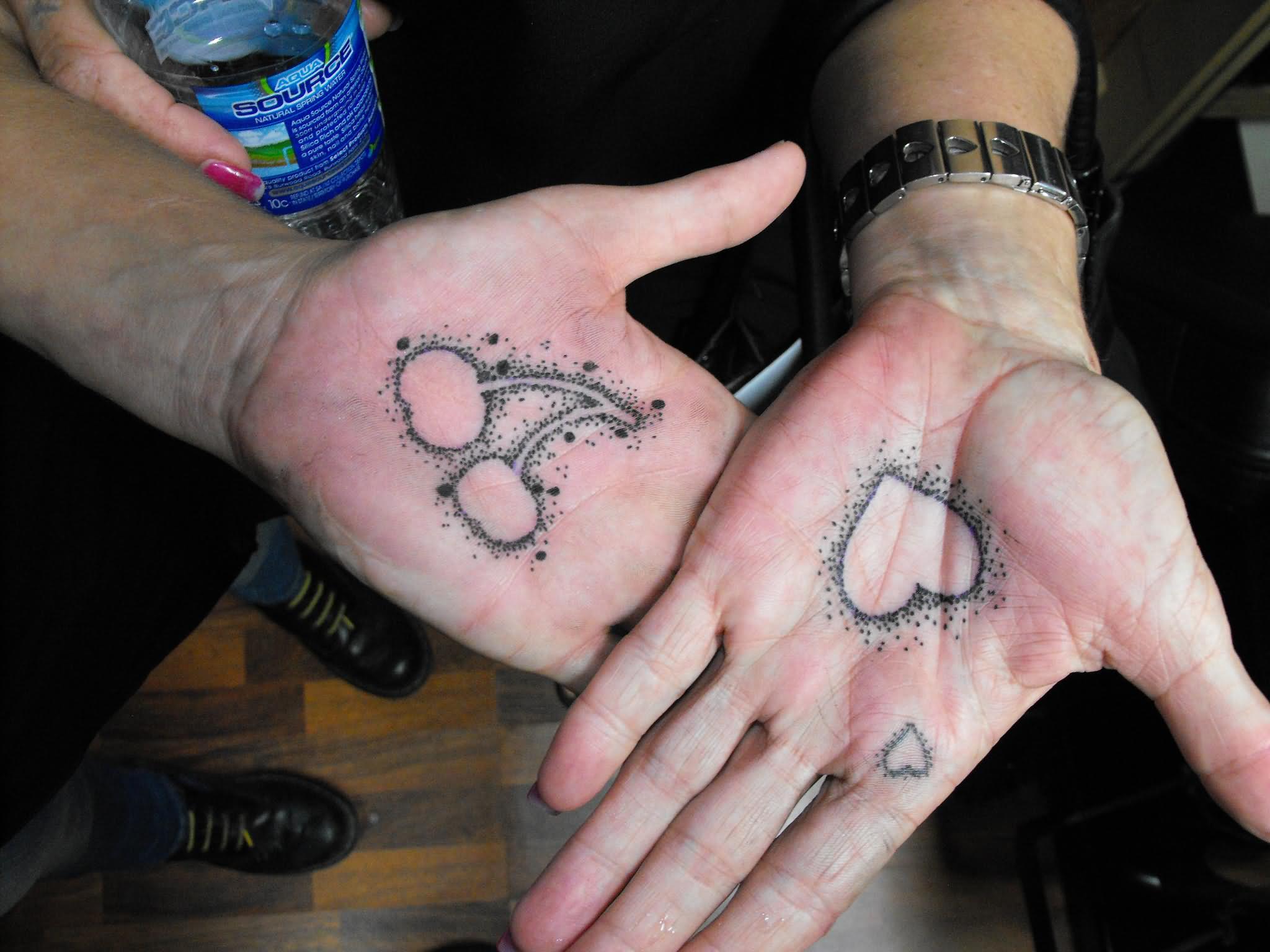 Black Outline Cheery And Heart Tattoo On Couple Hand Palm
