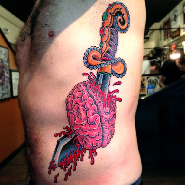 Colorful Dagger In Brain Tattoo On Man Side Rib