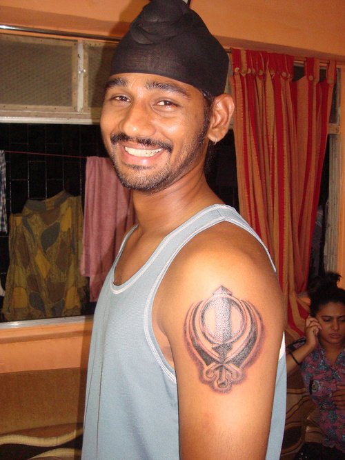 Black And Grey Sikhism Khanda Tattoo On Man Left Shoulder