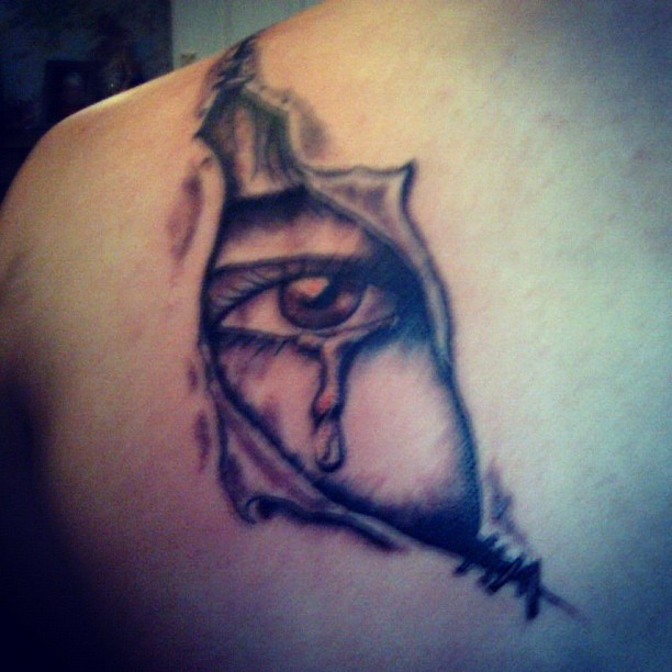 Black Ink Ripped Skin Crying Eye Tattoo On Left Back Shoulder