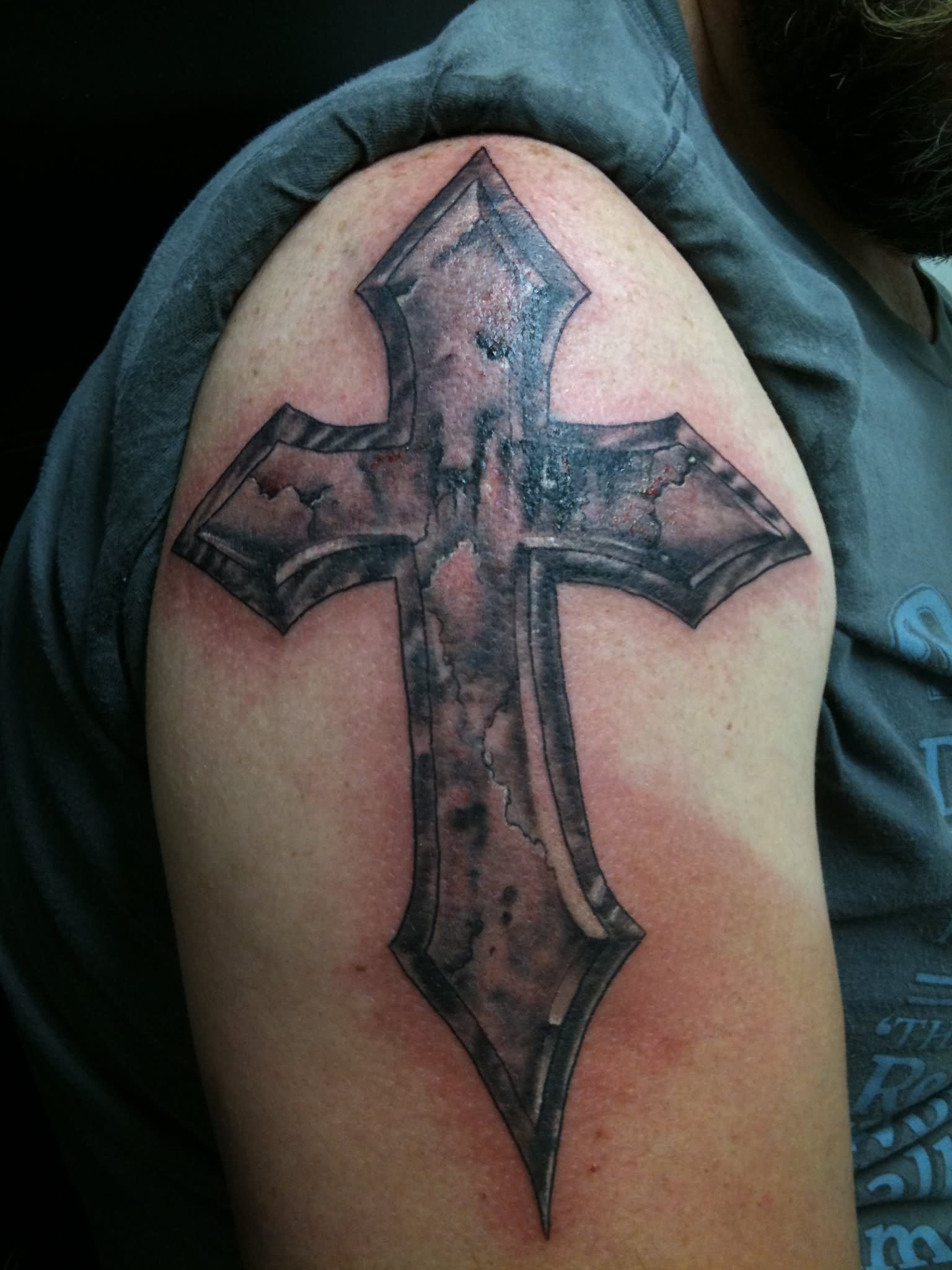 Black ink cracked stone cross tattoo on shoulder