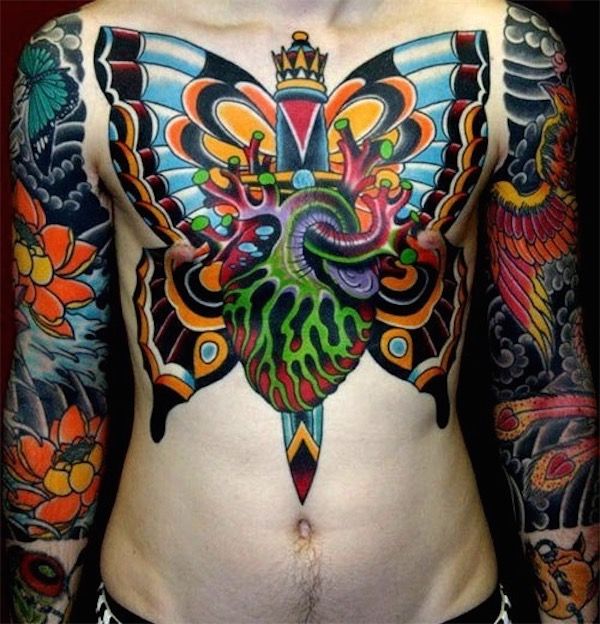 Colorful Dagger In Real Heart With Butterfly Wings Tattoo On Man Chest