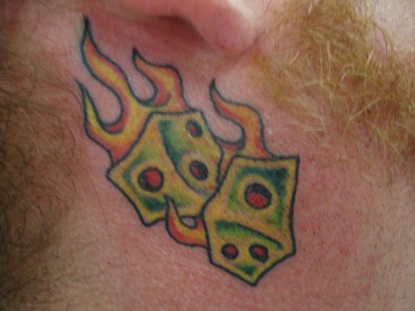 Colorful Dice In Flame Tattoo On Man Behind The Ear