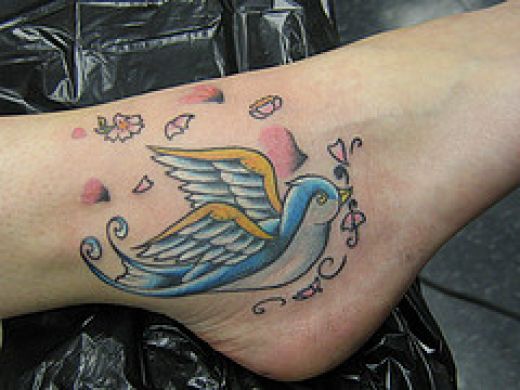 Colorful Flying Bird Tattoo On Ankle