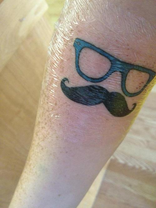 Specs With Hipster Mustache Tattoo On Forearm