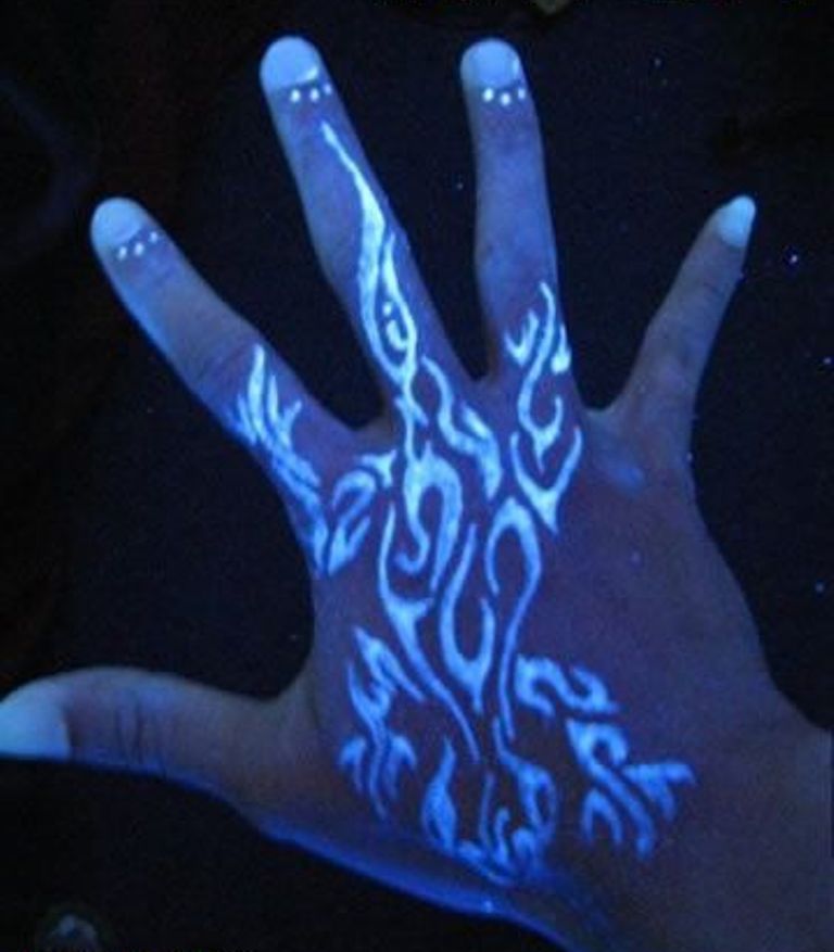 Tribal White Ink Tattoo On Hand Under Blacklight