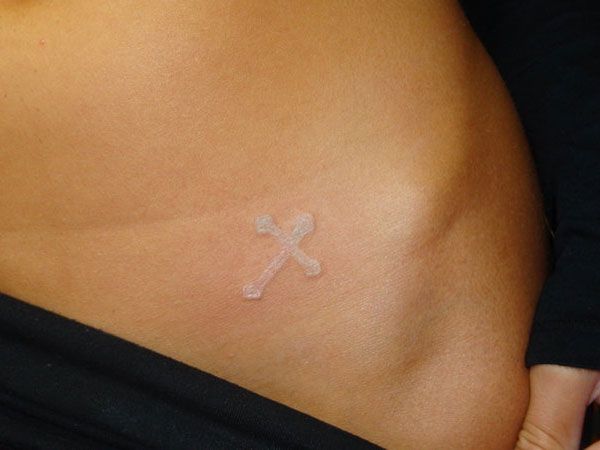 White Ink Cross Tattoo On Left Hip For Girls