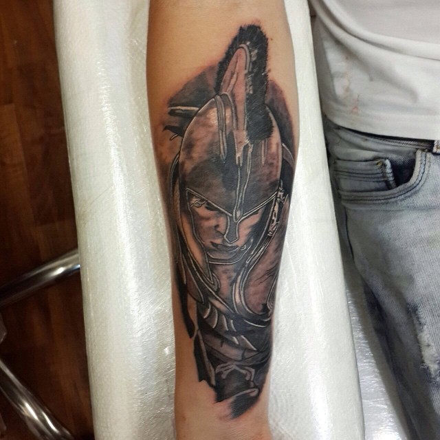Black And Grey Achilles Warrior Head Tattoo On Forearm