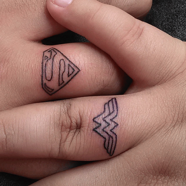 Black Outline Wonder Women And Superman Logo Tattoo On Finger