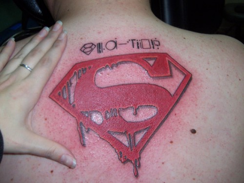 Melting Superman Logo Tattoo On Upper Back