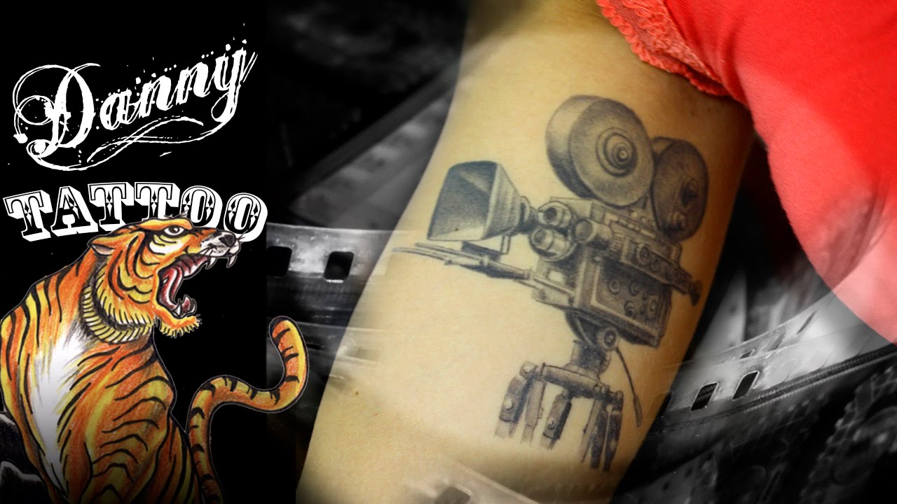 Black And Grey Movie Camera Tattoo On Bicep
