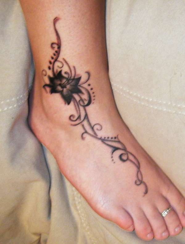 Black Flower With Swirl Tattoo On Foot