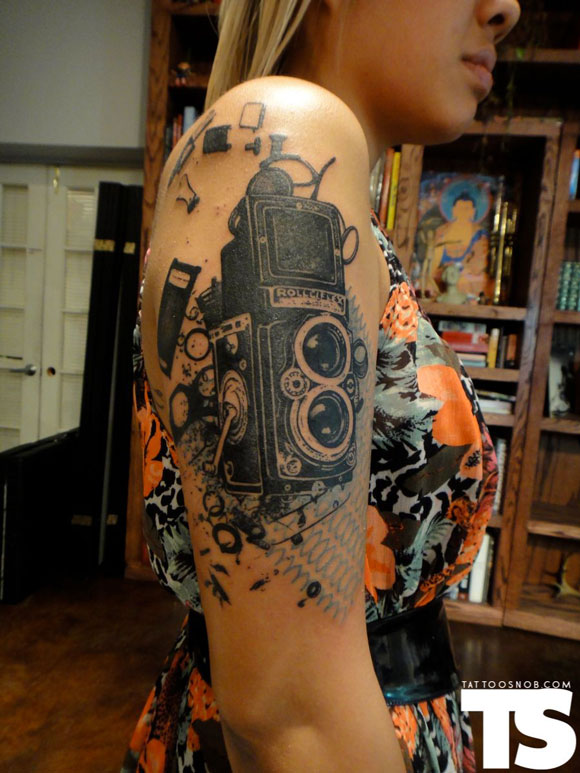 Black Ink Movie Camera Tattoo On Girl Right Half Sleeve