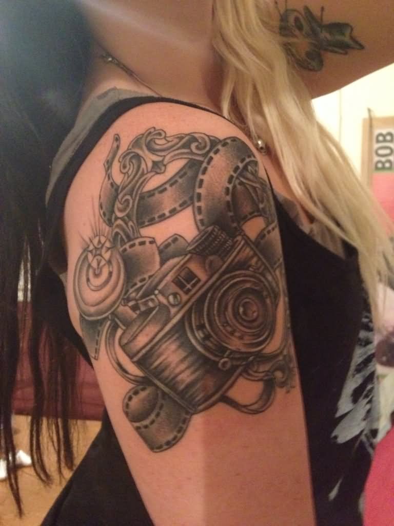 Black Ink Movie Camera With Reel Tattoo On Girl Right Shoulder