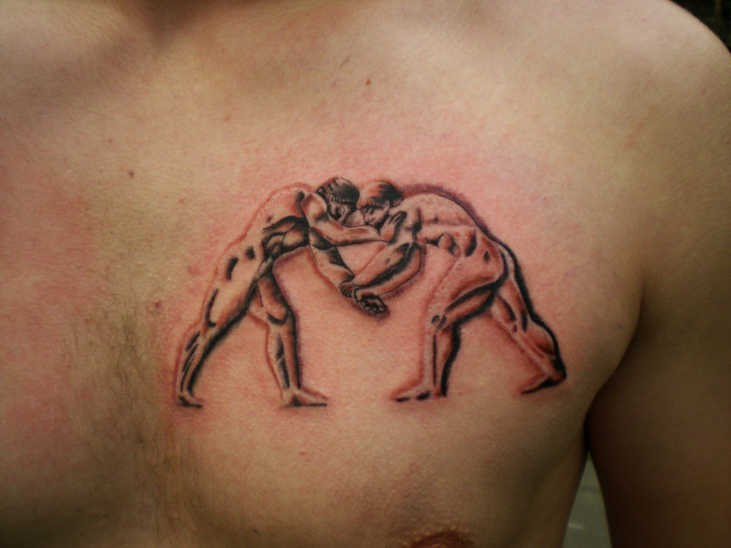 Black Ink Two Wrestler Fighting Tattoo On Man Chest.