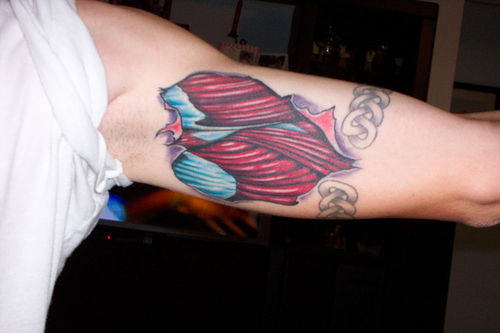 Blue And Red Ripped Skin Muscle Tattoo On Bicep