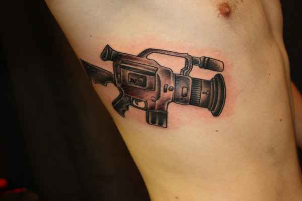 Latest Black Ink Movie Camera Tattoo On Man Side Rib