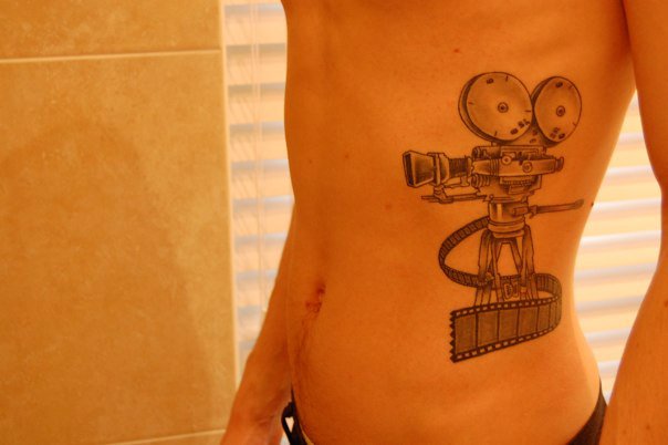 Movie Camera With Reel Tattoo On Man Side Rib