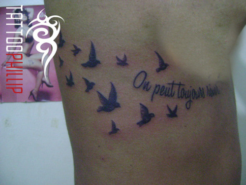 On Peut Toujours Rever Lettering With Flying Birds Tattoo On Under Breast