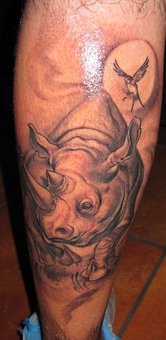 Black Ink Rhino With Flying Bird Tattoo On Leg