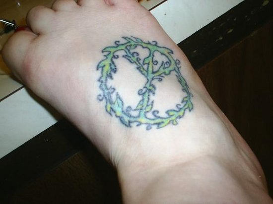 Awesome Green Ink Peace Logo Tattoo On Foot
