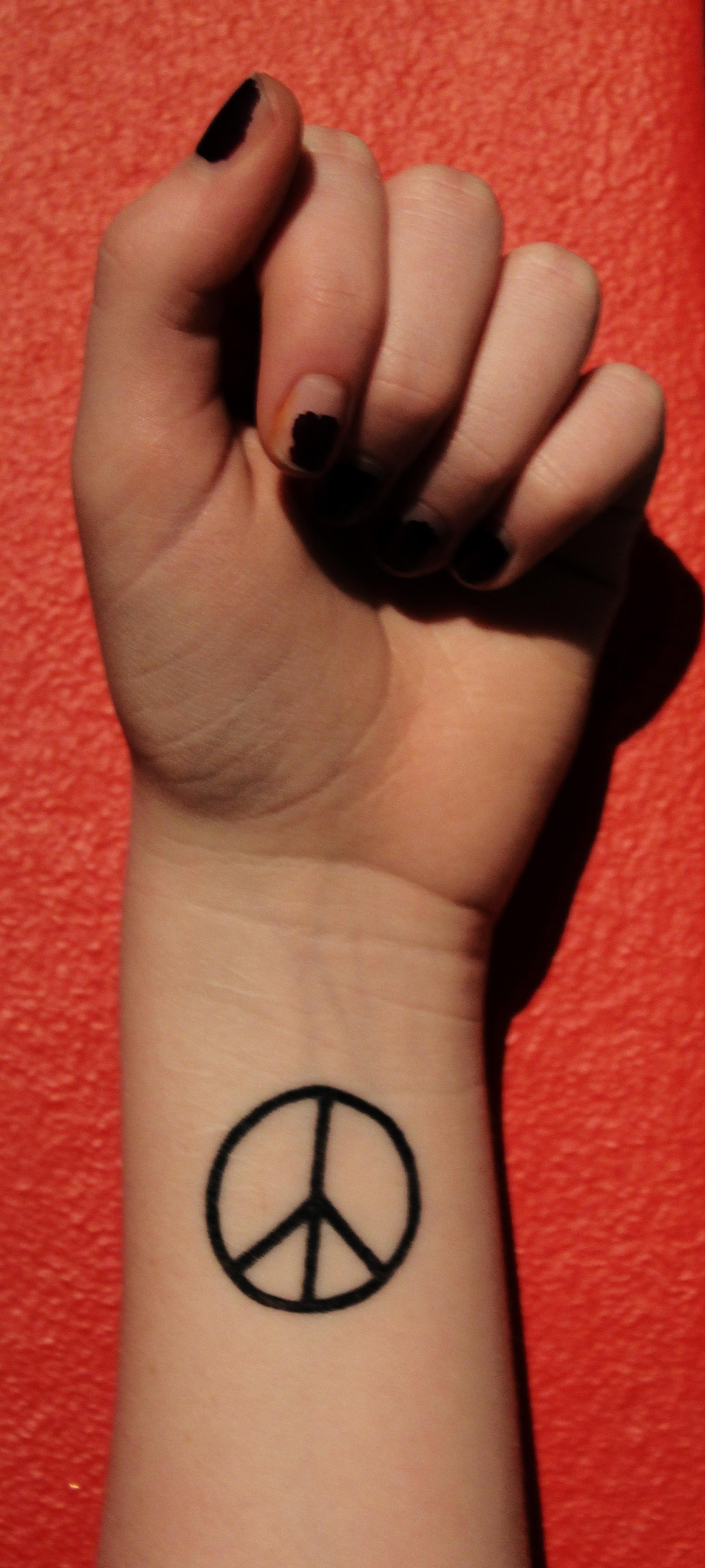 Black Peace Logo Tattoo On Girl Wrist