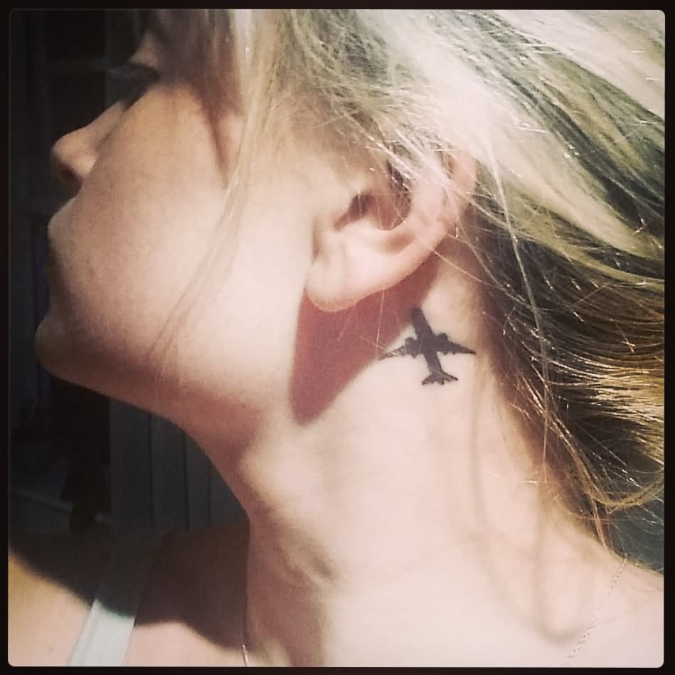 Black Ink Airplane Tattoo On Girl Behind The Ear